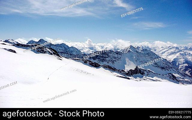 winter mountain landscape in the Austrian Alps with many backcountry skiers crossing a large glacier and a great background view of the Hohen Tauern mountains...