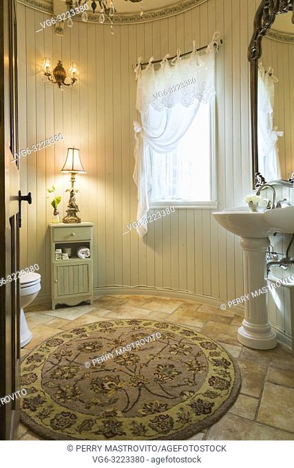 White porcelain pedestal sink, toilet and small wooden cabinet with lamp in guest bathroom inside a 2006 reproduction of a 16th century Renaissance castle style...