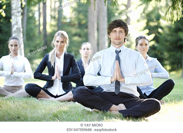 Business people practicing yoga in park