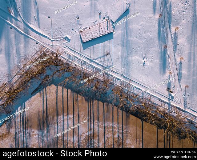 Russia, Leningrad Oblast, Tikhvin, Aerial view of snow-covered road stretching along frozen pond