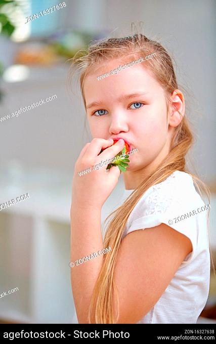 Blondes Kind beim Erdbeere essen zu Hause in der Küche