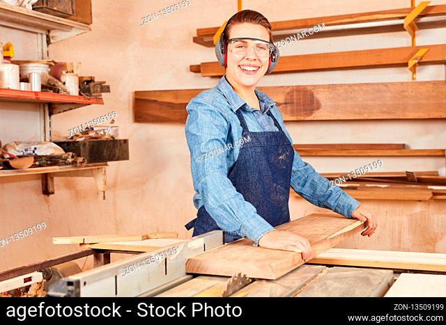 Junge Frau als Tischler Azubi sägt Holz an der Kreissäge in einer Tischlerei Werkstatt