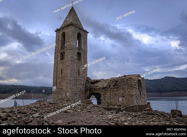 Bell tower of Sau fully exposed during the drought of 2022. Red sunrise in the swamp (Osona, Barcelona, Catalonia, Spain)
