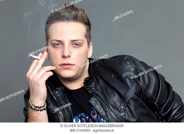 Young man in a leather jacket smoking a cigarette, portrait