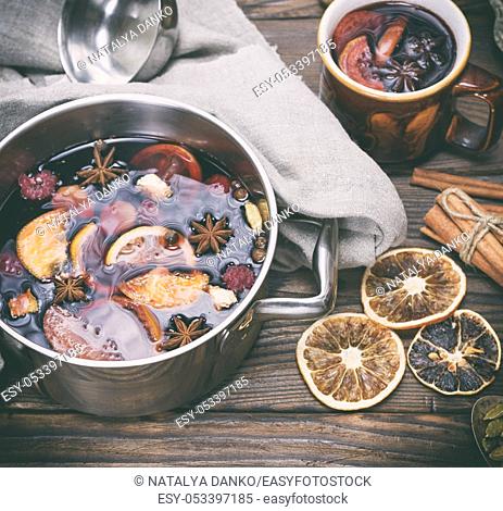 mulled wine in an iron saucepan on a brown wooden table, top view
