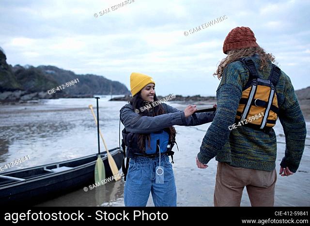 Young couple preparing for canoeing on beach