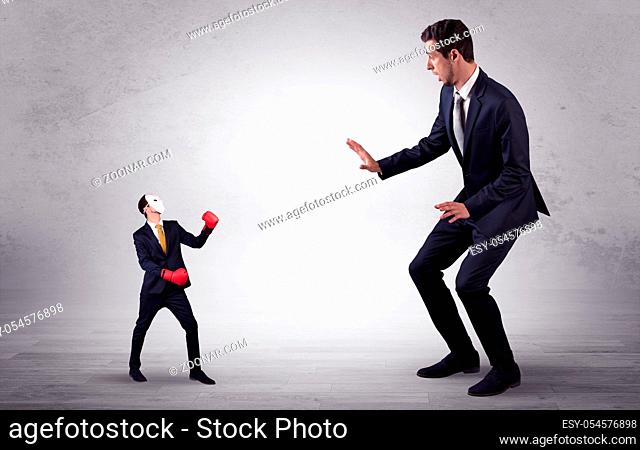 Big businessman being afraid of small masked businessman with box gloves in an empty room concept