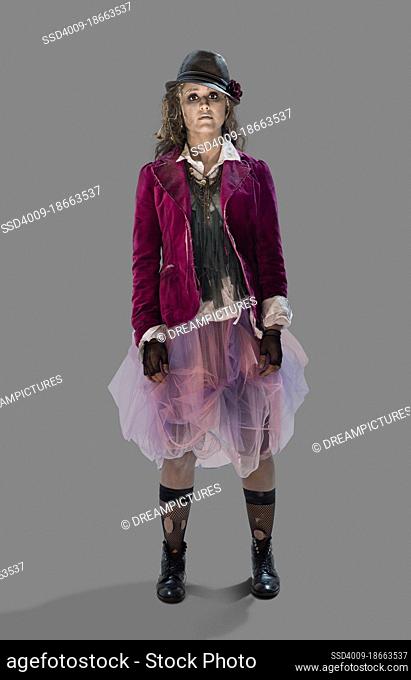 A dead looking Zombie woman Halloween costume looking into camera, against gray background