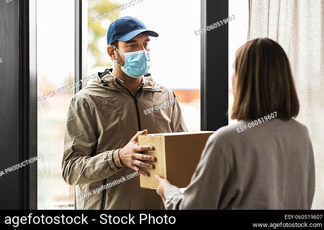 delivery man in mask giving parcel box to customer