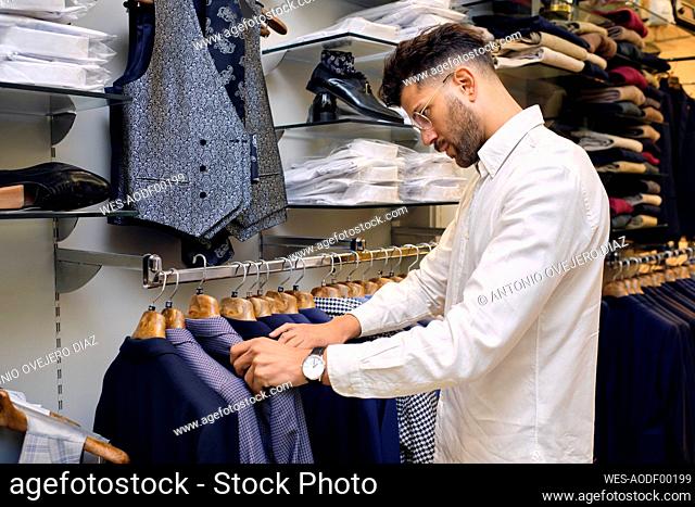 Customer browsing shirts on rack in tailors boutique