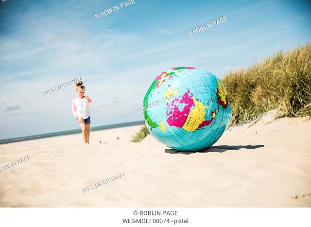 Globe on the beach with girl in background
