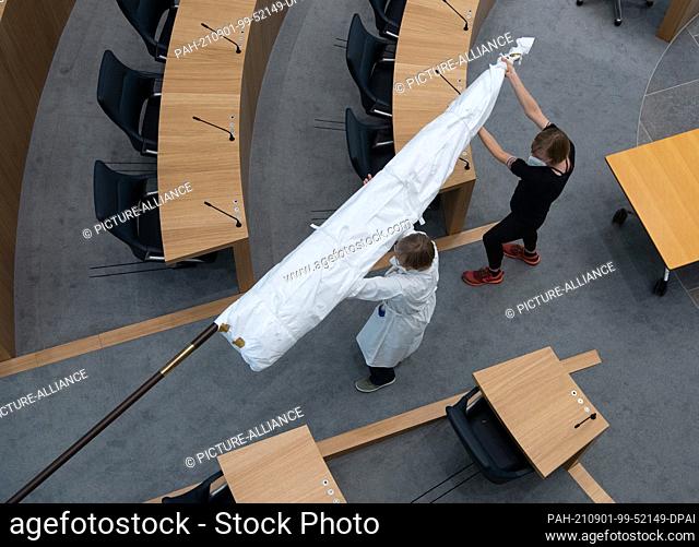 01 September 2021, Rhineland-Palatinate, Mainz: Two restorers carry the still packed historical ""Hambach flag"" in the plenum of the state parliament in Mainz