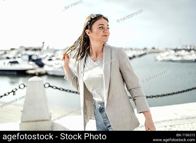 Portrait of young woman walking by marina in Faro, Portugal, Europe