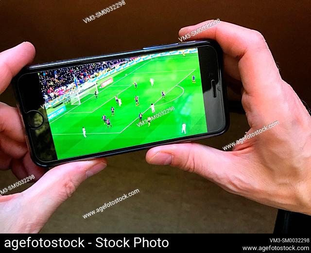 Hands holding a smartphone showing a football match