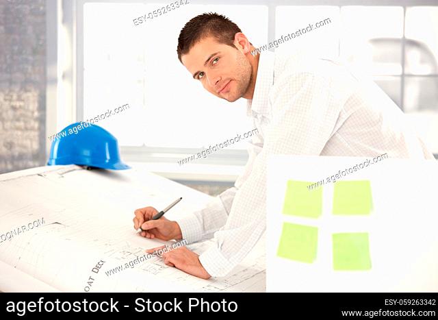 Handsome young engineer drawing plans in bright office
