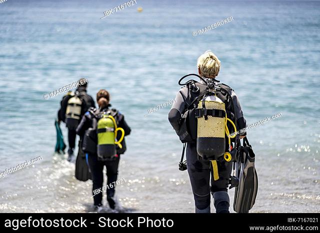 Three scuba divers with all equipment heading to the sea, Andalusia, Spain, Europe