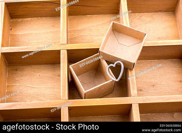 Open cardboard box inside a wooden box with compartments and a heart