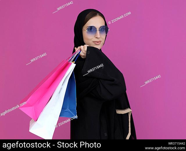 Happy Muslim woman posing with shopping bags. Arabic woman wearing traditional islamic black clothes and sunglasses representing rich and luxurious lifestyle...