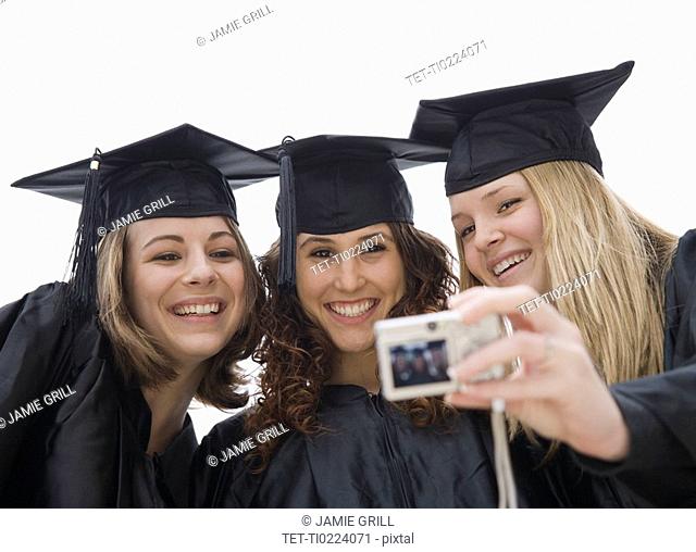 Teenage girls taking own photograph on graduation day