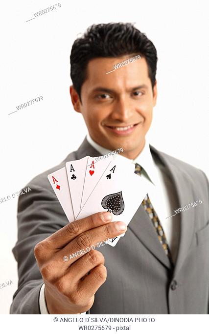 Businessman holding four aces of playing cards in his thumb index and middle finger of right hand MR703T