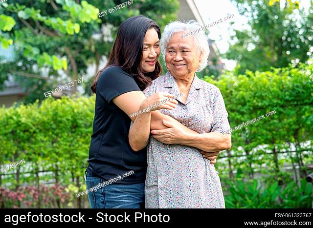 Asian elderly woman with caregiver daugther walking and hug with happy in nature park