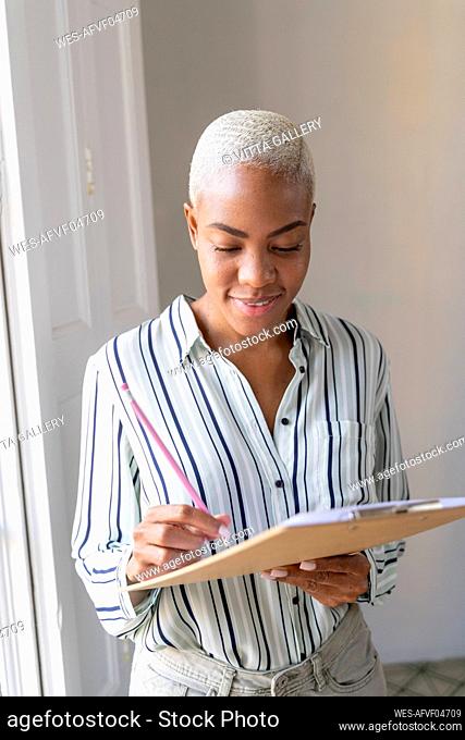 Smiling woman holding clipboard and pencil in office