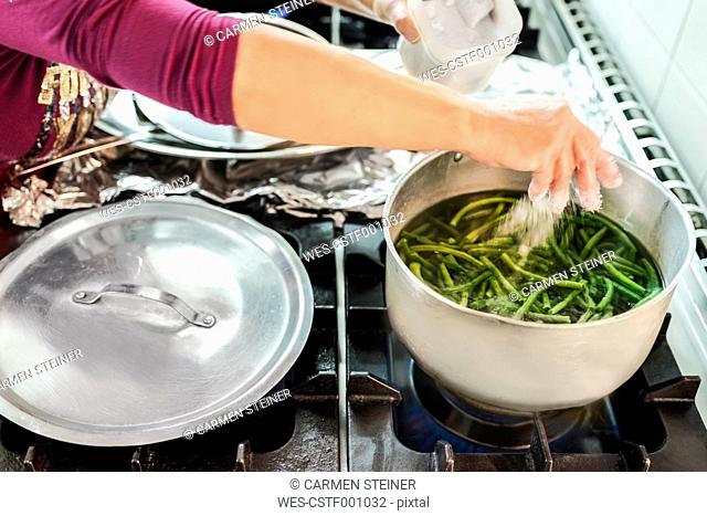 Woman boiling green beans in canteen kitchen