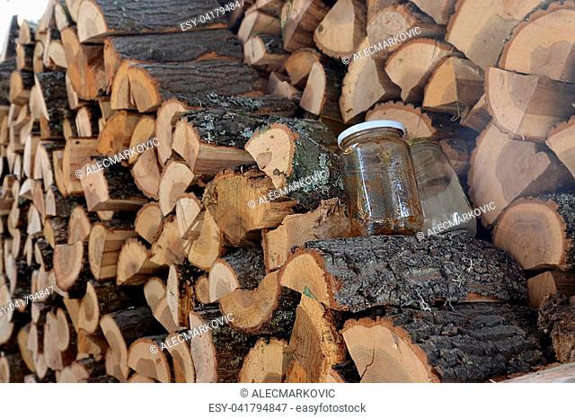 Lumber cut for fire and piled up in front of a house, with two empty jam jars. Ready for winter