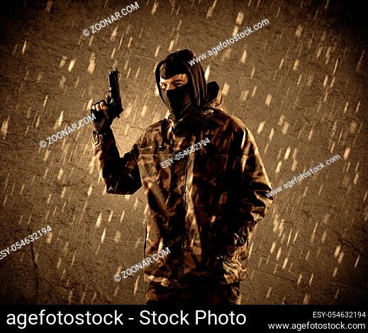 Portrait of dangerous heavily armed terrorist soldier with mask on grungy rainy background