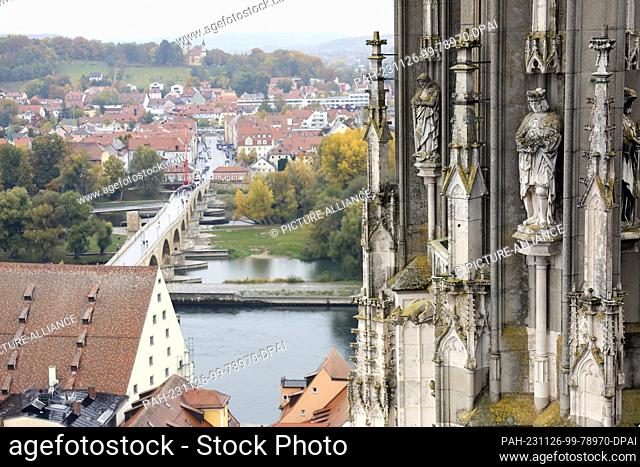 FILED - 24 October 2023, Bavaria, Regensburg: Sandstone figures covered in moss stand at a height of around 60 meters on a tower of Regensburg Cathedral