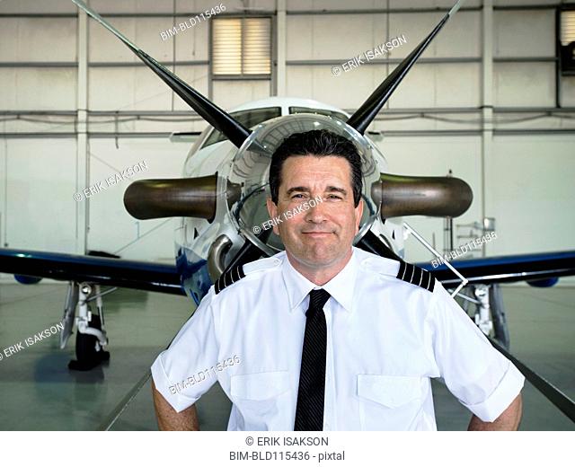Caucasian pilot smiling in hangar