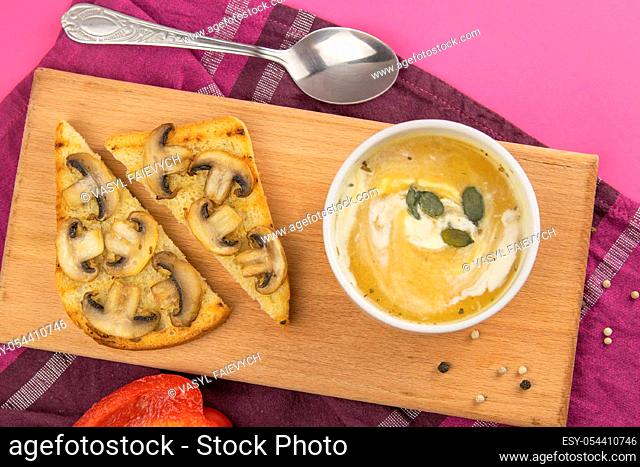 Pea soup with croutons stands on a green towel, next to there are tomatoes, toasts of pumpkin seeds, everything stands on the yellow table