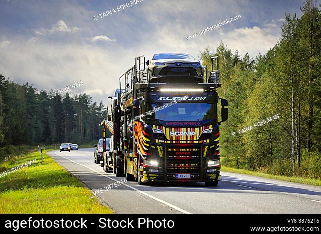Unique vehicle carrier Scania R650 of Kuljetus J. Kivi transports new cars on road 25, high beams on briefly. Raasepori, Finland. September 9, 2021