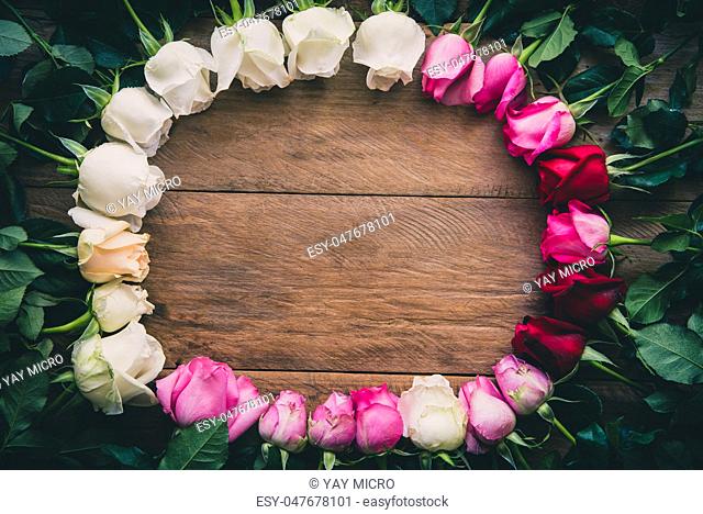 Colorful roses lined up on a wooden floor with space for writing your message