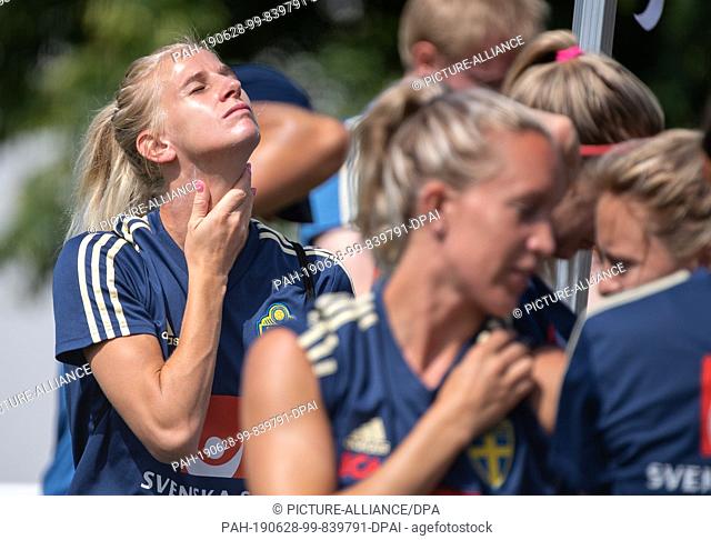 28 June 2019, France (France), Fougeres: Football, women: World Cup, national team, Sweden, training: Sofia Jakobsson (l) applies sun cream