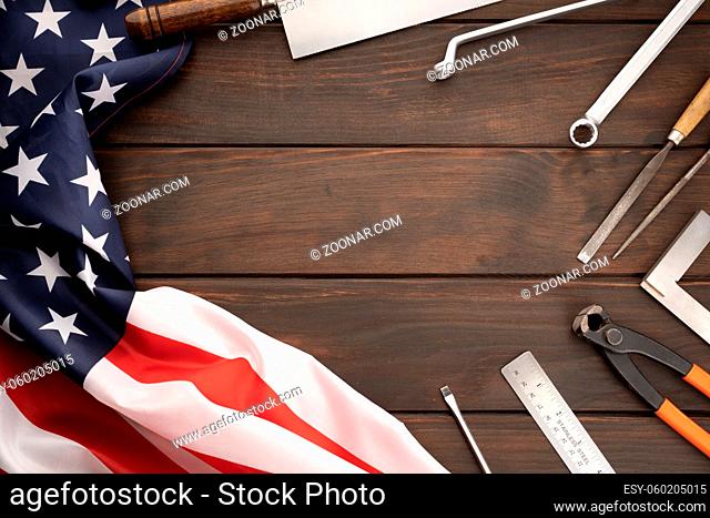 Top view of american flag and work tools on wooden tabletop with copy space. Labor day concept background