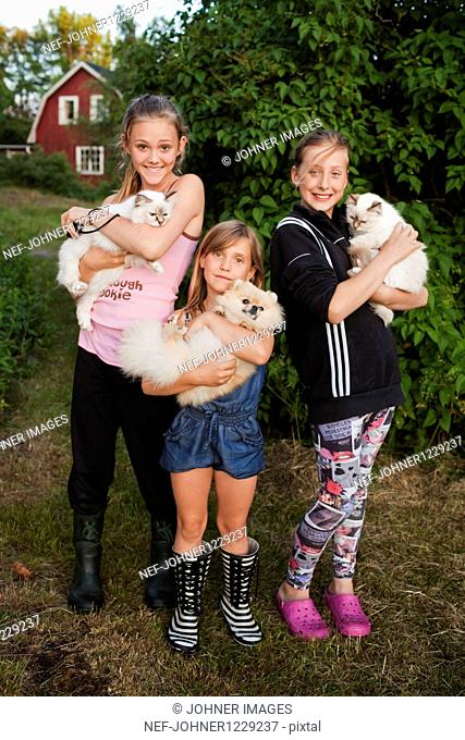 Portrait of three girls holding pets