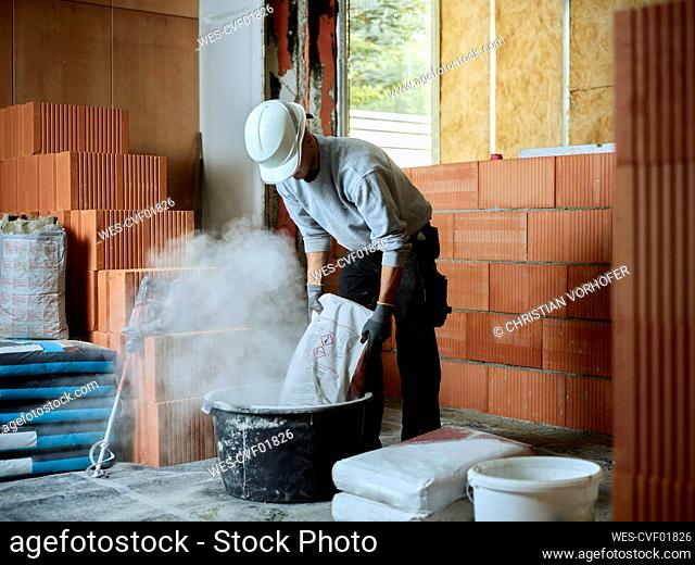Bricklayer putting cement in tub at construction site