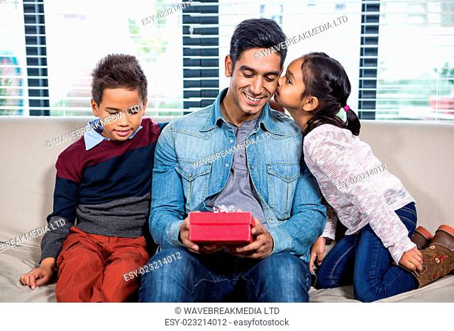 Happy father receiving a gift from his children in living room