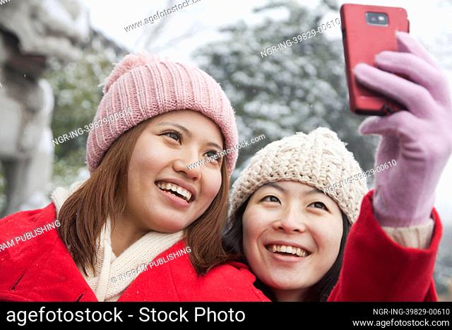 Two friends taking picture with cell phone in snow