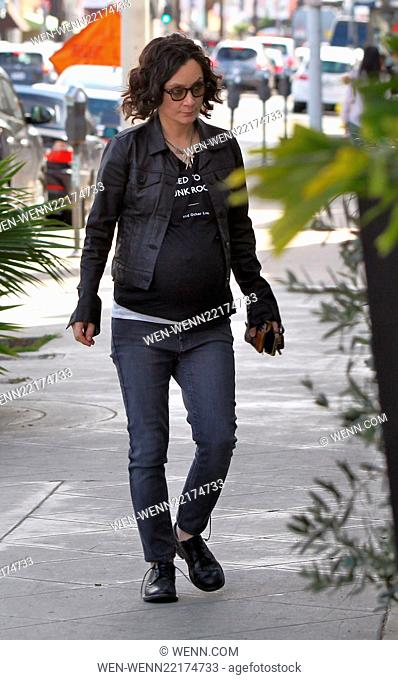 Heavily pregnant Sara Gilbert taking some long strides as she walks with her shoe laces undone in her sensible black shoes