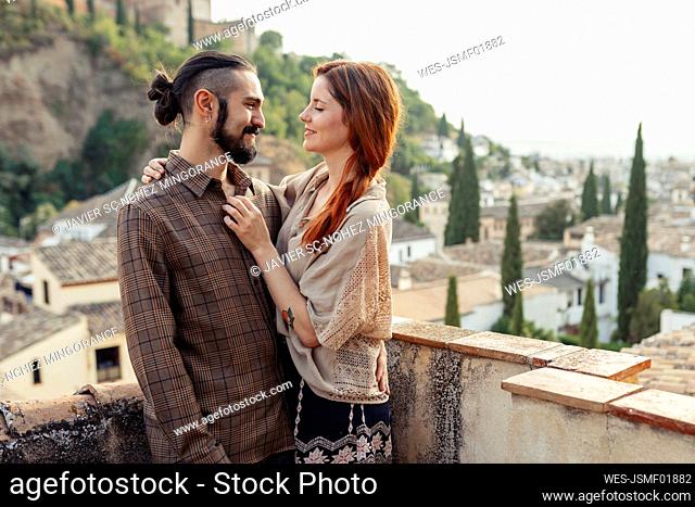 Man and woman embracing while standing on rooftop