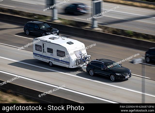04 September 2022, Hessen, Eschborn: A car with a caravan is driving on the highway. For many vacationers from the German states of Hesse