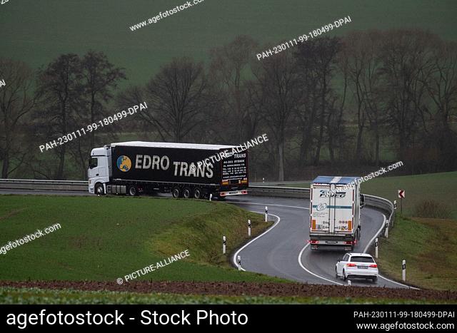 11 January 2023, Lower Saxony, Scheden: Trucks bypass the closed Autobahn 7 on a country road. Highway 7 in southern Lower Saxony has been closed since Monday...