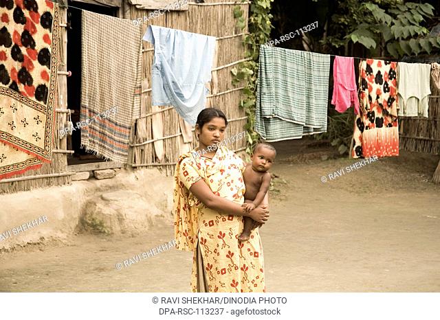 Woman and child looking sad standing in front of house hanging cloths to dry poor life in small village district Manik gunj ; Bangladesh