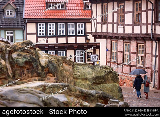 29 December 2021, Saxony-Anhalt, Quedlinburg: Visitors against through a narrow alley in the world heritage city. With a historically built-up town centre...