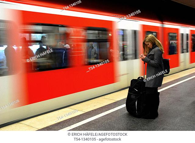 A young woman with luggage, SMS reads as the train enters into the Metro station