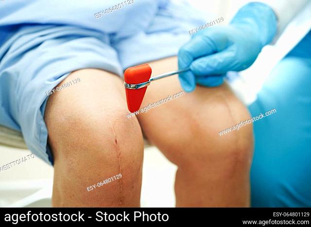 Asian doctor knock on knee reflex nerve for check and treatment senior patient in hospital
