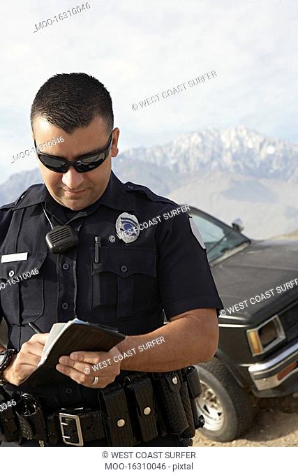 Police officer taking notes in front of car