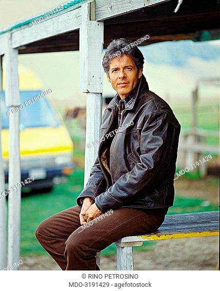 Italian song writer Claudio Baglioni (Claudio Enrico Paolo Baglioni) posing seated. On the background there is the yellow van which drove him on his mini-tour...